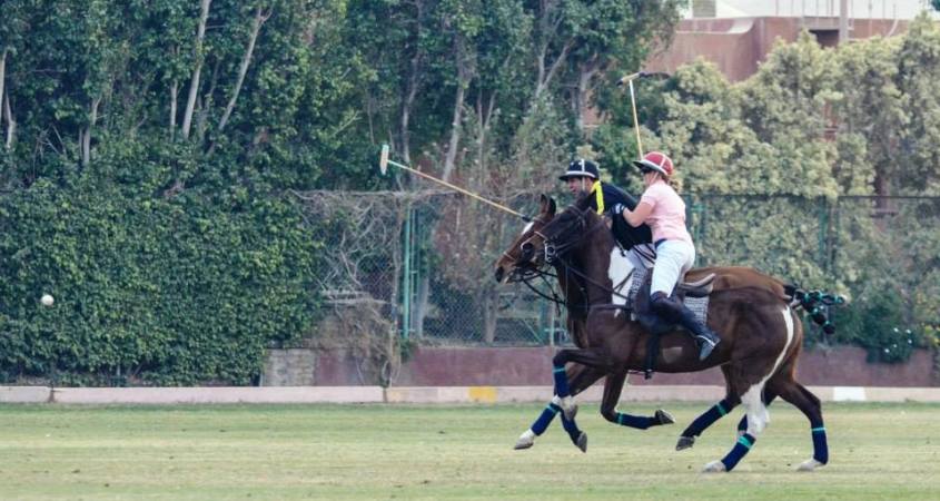 Two riders galloping next to each other playing polo